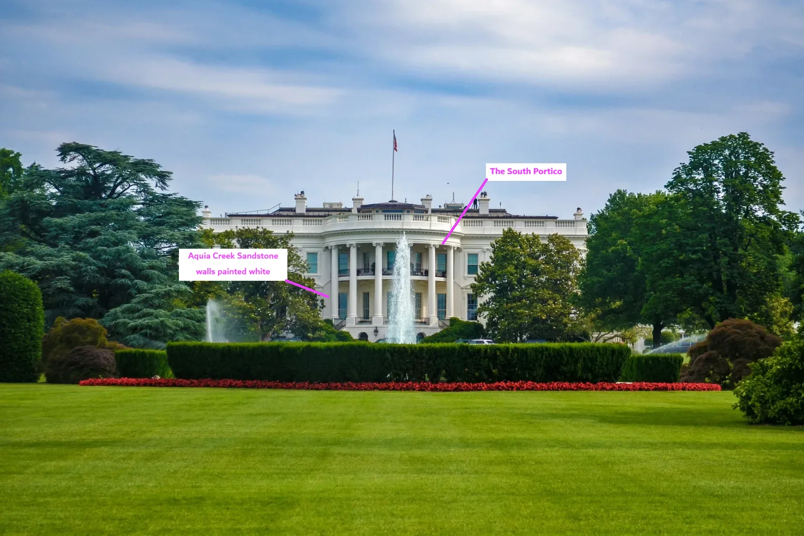 The White House seen across the South Lawn: a white neoclassical building with a curved, columned portico in the centre, a fountain in front of it, a low hedge and a row of red flowers, framed by large trees. Labels mark the South Portico and the Aquia Creek sandstone walls painted white